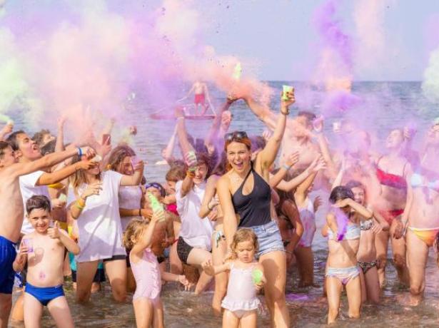 Persone che si divertono in spiaggia con polveri colorate.