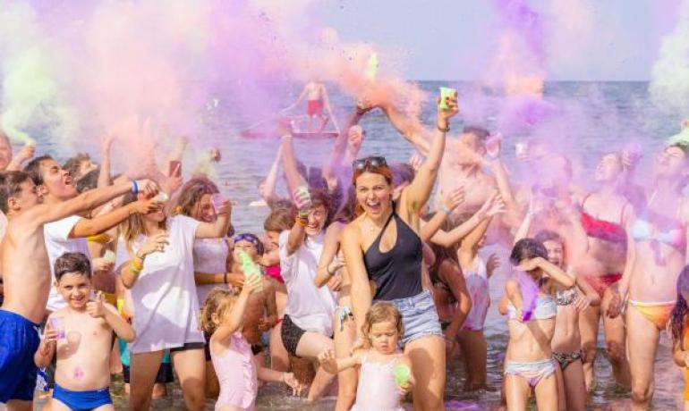 Menschen haben Spaß am Strand mit bunten Pulvern.